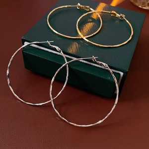 Boucles d'oreilles créoles martelées en or et argent sur un coffret cadeau luxe