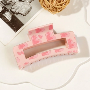 Detail of pink rectangular hollow hair claw clip with hand-painted heart patterns