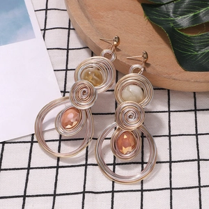 Close-up of Bohemian heart drop earrings with wire-wrapped pearls on checkered fabric