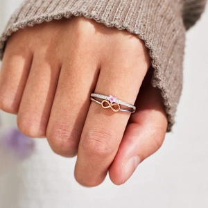 Detail of s925 silver ring featuring pink heart stone and infinity symbol on hand