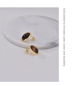 Macro view of gold plated tiger eye stone stud earrings with a polished round finish