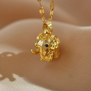 Macro shot of gold elephant pendant with sparkling cubic zirconia on beige fabric