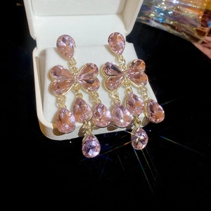 Gros plan de boucles d'oreilles papillon en cristal rose avec pampilles étincelantes