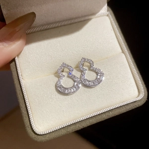 Macro shot of silver hollow gourd earrings with cubic zirconia in a velvet gift box