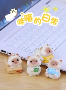 Detailed view of four cute miniature resin cat figurines on a wooden desk with a laptop