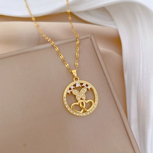 Elegant gold butterfly and heart pendant necklace with rhinestones on a beige jewelry box