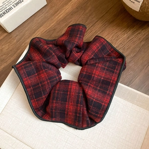 Vue détaillée d'un grand chouchou à carreaux rouge et noir avec texture tissée sur plateau