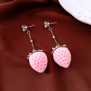 Detailed view of zircon pink flocked strawberry drop earrings on dark brown fabric.