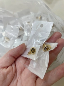 Detailed macro of coffee bean shaped tiger eye studs in protective clear packaging