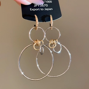 Macro shot of geometric layered hoop earrings in contrasting gold and silver finishes