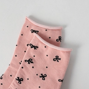 Detail of pink cotton socks with black polka dots and butterfly bow patterns