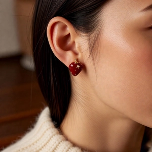 Detailed close-up of a red strawberry earring with gold plating and sparkling zircon stone