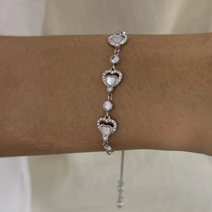 Detail of adjustable silver bracelet with zircon heart and white shell inlay on wrist