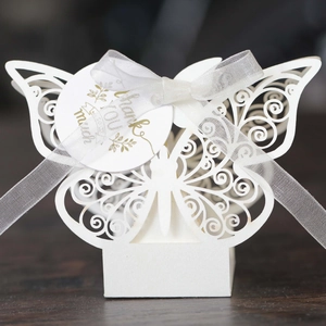 Macro shot of white laser-cut butterfly favor box with ribbon and gold foil thank you tag