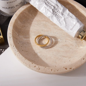 Detailed shot of interlocking gold and silver rings with cubic zirconia on a stone tray