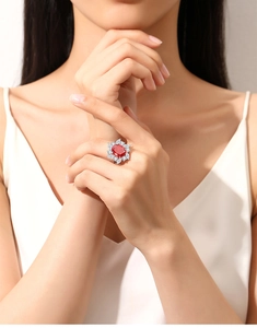 Close-up of heart-shaped red gemstone ring with floral zircon setting on model finger