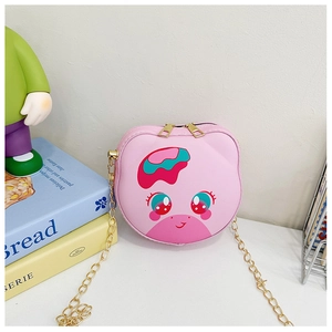 Close-up of pink cartoon small crossbody bag with gold chain strap on a desk setting