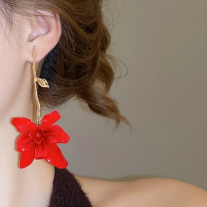 Close-up of model wearing red layered flower drop earrings with golden curved stems