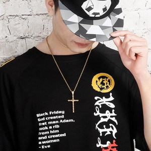 Gold cross pendant necklace with twist chain worn by a male model against a brick wall