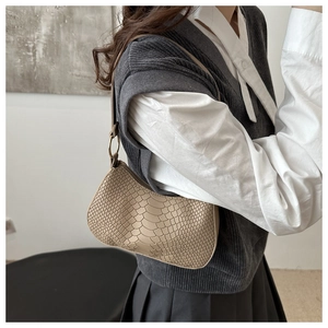 Detail of snake pattern shoulder bag with golden ring hardware and curved silhouette