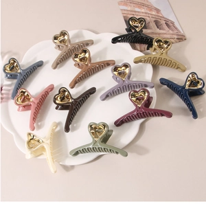 Flat lay of colorful heart-shaped hair claw clips in Morandi tones with gold hollow patterns