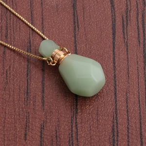 Macro shot of green aventurine flame-shaped perfume bottle pendant with golden chain