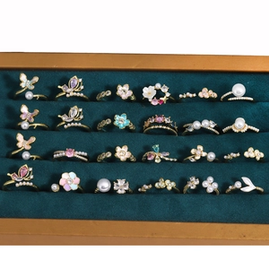 Close-up of enamel butterfly and flower rings with colorful zircon in a velvet box
