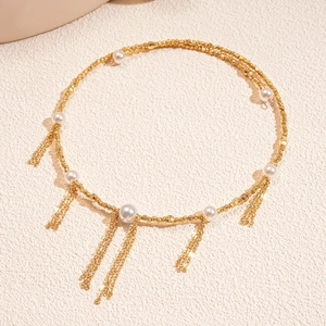 Detail of gold woven necklace featuring white pearl accents and long tassel chains