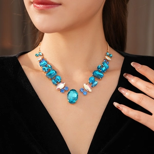 Macro shot of blue crystal geometric pendant necklace on model with golden metal setting