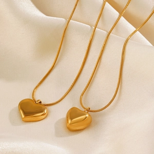 Polished 18K gold plated stainless steel heart pendant necklaces on beige satin cloth