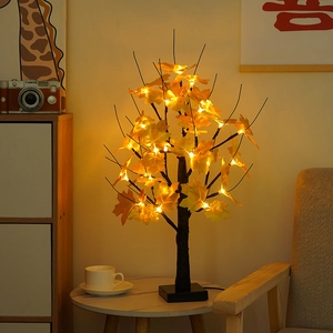 Cozy warm LED maple leaf tree light with black trunk on a wooden table at home