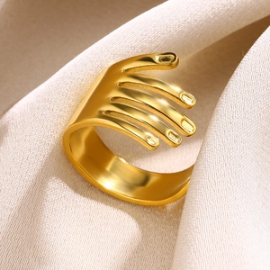 Macro view of gold plated palm hand ring on beige fabric showing refined polished metal