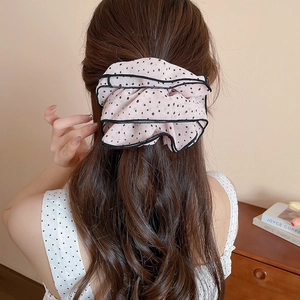 Detail view of pink chiffon hair scrunchie with black polka dots and tiered ruffle design