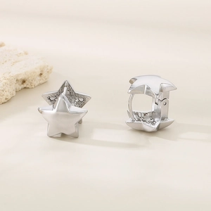 Detailed view of silver star earrings on a beige surface with natural stone accent