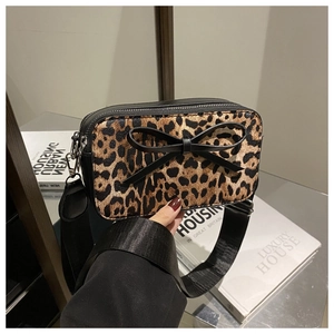 Detailed view of leopard print crossbody bag with a black bow and wide shoulder strap