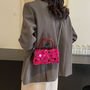 Fashionable rose red sequin crossbody bag with chain strap styled on a grey blazer jacket