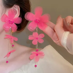 Pink chiffon floral tassel earrings with golden chain and beads on a model side view