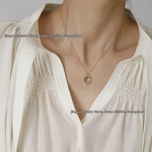 Detail of moon and star coin pendant on a gold necklace worn by a model