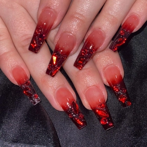 Long coffin nails with red and black ombre gradient and sparkling luxury gemstones