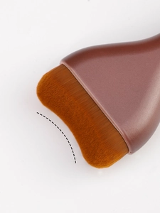 Macro shot of wide flat foundation brush with dense synthetic bristles and curved tip