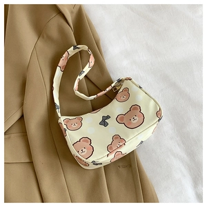 Close-up of cute cartoon bear print and black bow detail on a beige shoulder bag