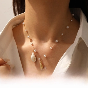 Détail du pendentif étoile de mer et perles sur collier doré avec breloque conque