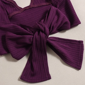 Detail of dark purple rib-knit fabric featuring a decorative knot design and texture