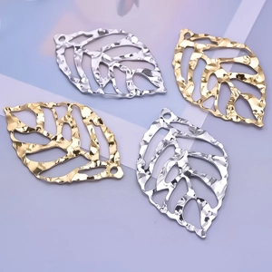 Detail of hollow leaf pendants in gold and silver finish with hammered metal texture