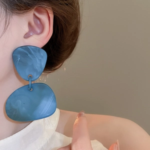 Detailed side view of a model wearing oversized blue marble texture geometric earrings