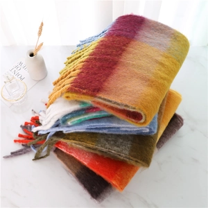 Detailed view of stacked colorful plaid scarves with soft fringe and thick knit texture