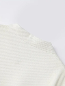 Dettaglio della trama in maglia a costine e della finitura del colletto bianco di una polo