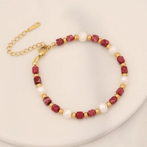 Detail of beaded bracelet with red stone, white pearls, and gold lobster clasp
