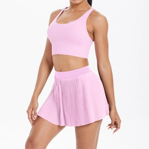 Detail of high-waisted pleated skirt and pink sports bra in two-piece yoga set
