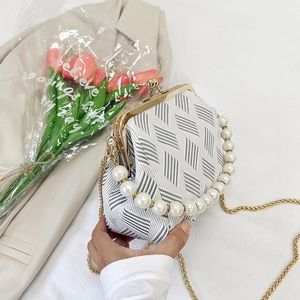 Close-up of geometric fabric shell bag with pearl handle and golden clasp detail